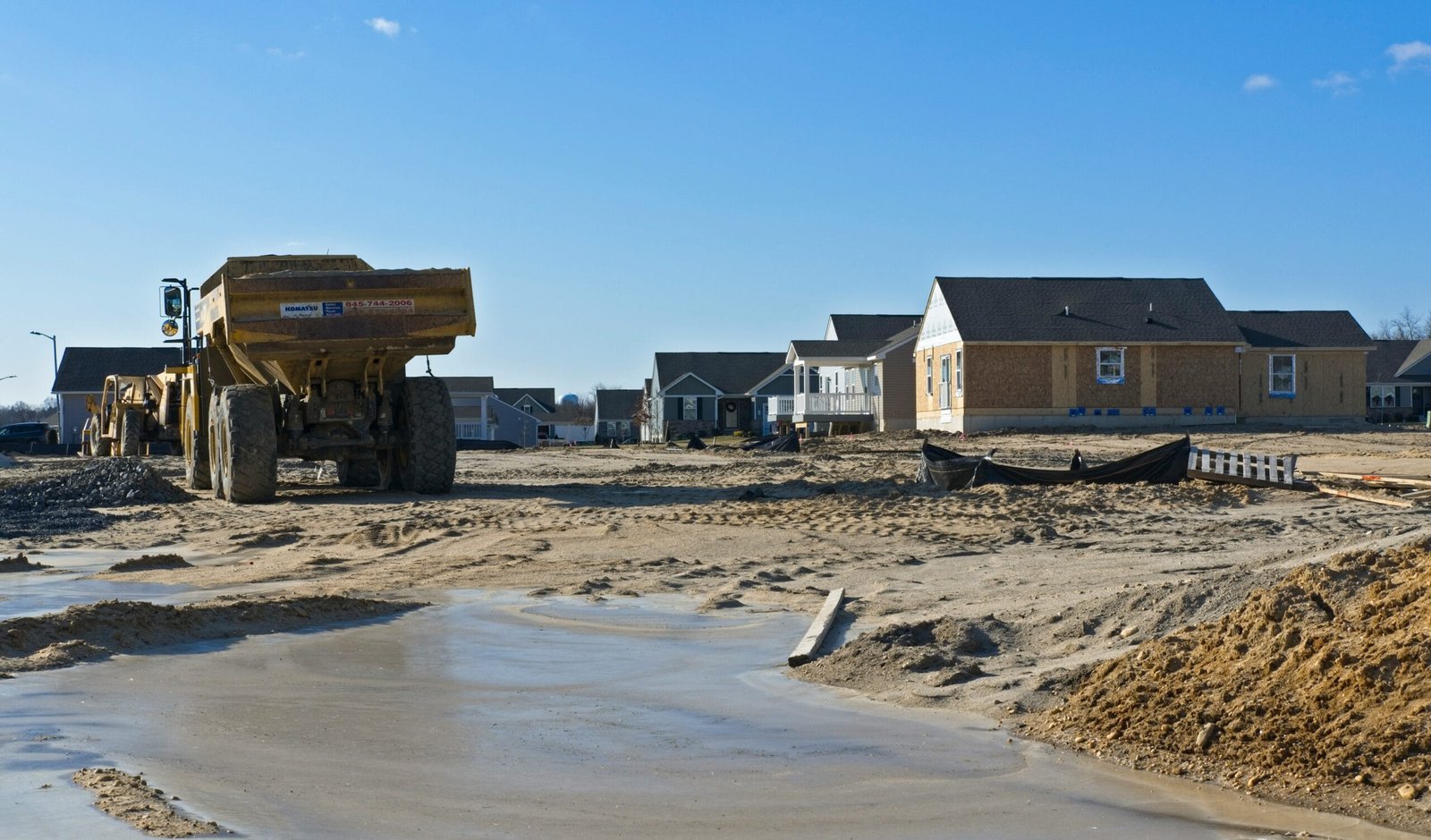 a construction site with a dump truck and houses in the background